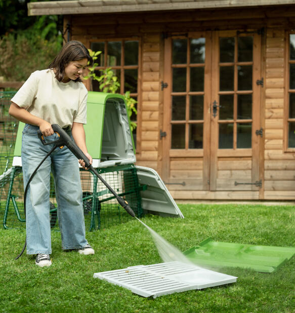woman pressure washing the eglu go up chicken coop roosting bars